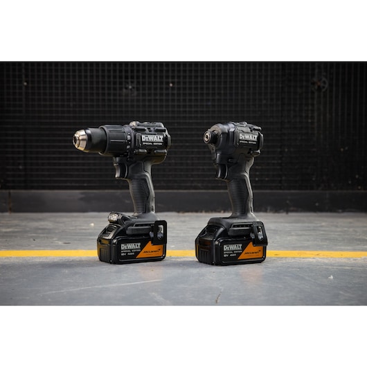 Two DEWALT cordless power tools with McLaren branding are standing side by side on a workshop floor.