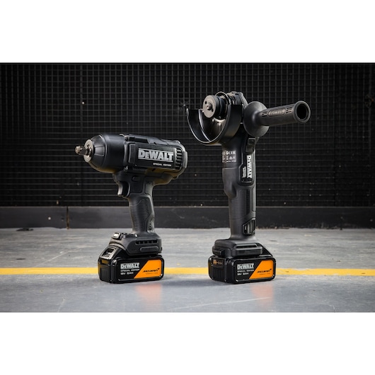 Two DEWALT cordless power tools with McLaren Special Edition batteries on a workshop floor.