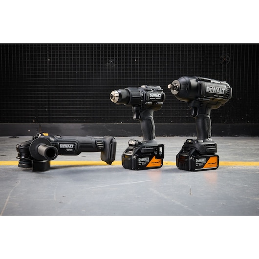 DEWALT x McLaren F1 Team 18V XR Special Edition Grinder, Hammer Drill Driver and Impact Wrench with 5Ah batteries standing on a concrete floor