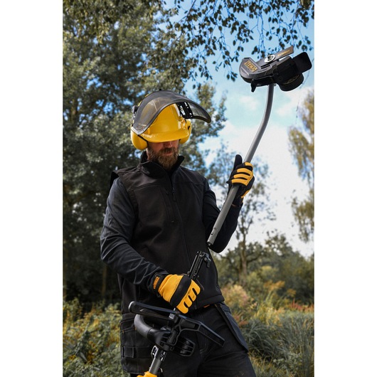 DEWALT DCMASED9N, DCMASED9N-XE user outdoors with safety gear, holding photography equipment.