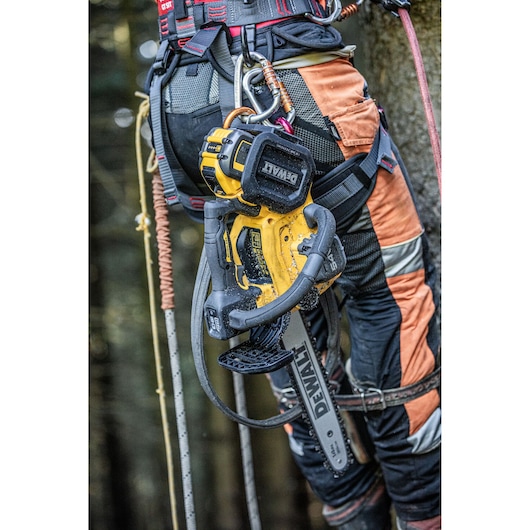 DEWALT chainsaw attached to arborist's harness and gear in a forest setting.
