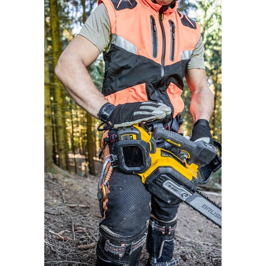 Person in safety gear holding a DEWALT chainsaw in a forest.