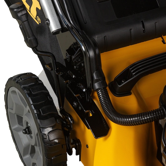 Close-up view of a DEWALT lawnmower showing part of the rear wheel, the handle, and components including a black flexible tube and the yellow body.
