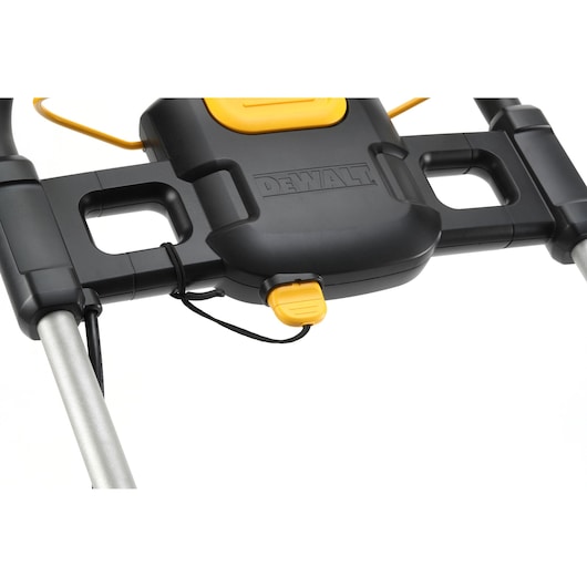 Close-up view of the handle and control panel of a DEWALT lawn mower, model DCMW564N, showing black and yellow plastic components and metal rods.