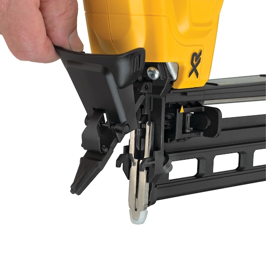 Close-up of a DEWALT nail gun being adjusted by hand, showing the tool’s mechanism and yellow outer casing.