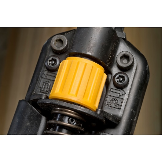 Close-up of a DEWALT tool component, showing a yellow adjustment knob and surrounding black plastic housing with metal screws.