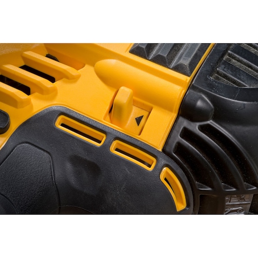 Close-up of a DEWALT power tool, showing yellow and black plastic parts and a switch with a directional arrow.