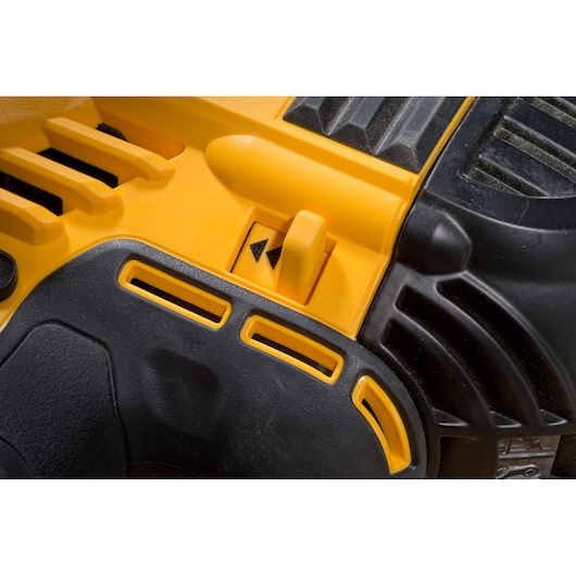 Close-up of a DEWALT power tool surface showing a yellow and black plastic housing with vent slots and a switch featuring two arrow symbols.