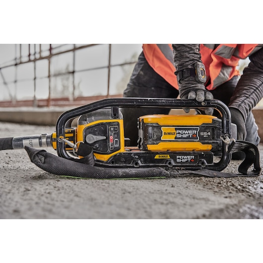 DEWALT Power Shift tool placed on concrete, handled by a worker wearing gloves and an orange safety vest.