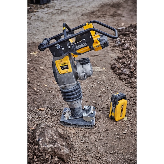 DEWALT cordless rammer with battery on a construction site, placed on soil and gravel.