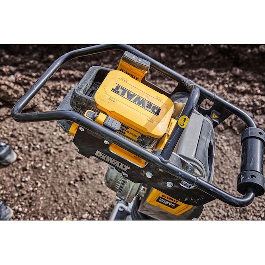 DEWALT DCPS660N power tool with yellow battery, shown outdoors with metal handle and soil in the background.