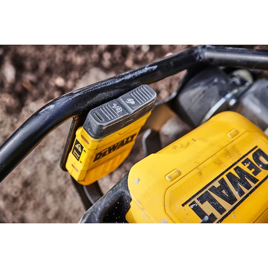 Close-up of a DEWALT yellow power tool with battery attached, placed outdoors on a metal frame.