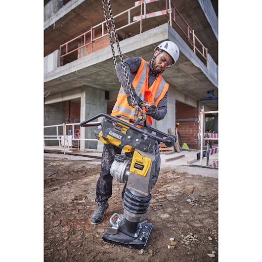 DEWALT DCPS660N compactor handled by person in safety gear at construction site.