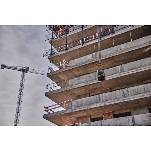 DEWALT tool being lifted by a crane at a multi-story concrete building construction site.