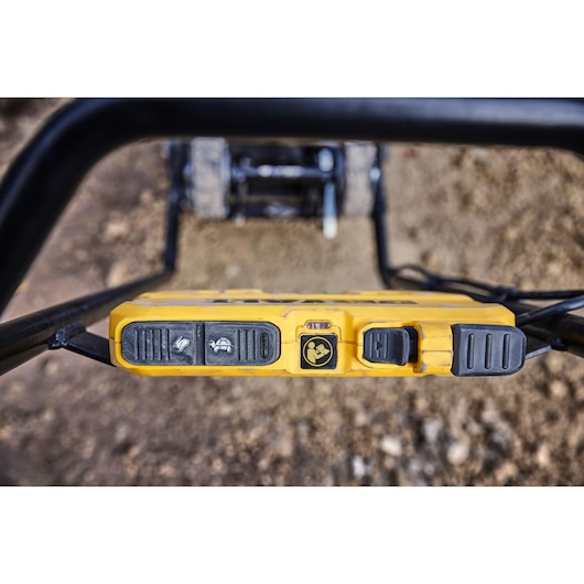 Close-up of DEWALT DCPS7154N control panel with buttons and safety icons, positioned on outdoor equipment.