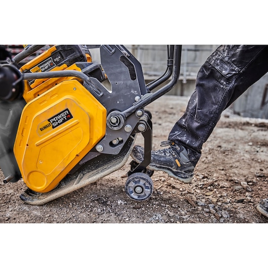 A DEWALT Power Shift tool being operated outdoors by a person wearing work boots and black pants.