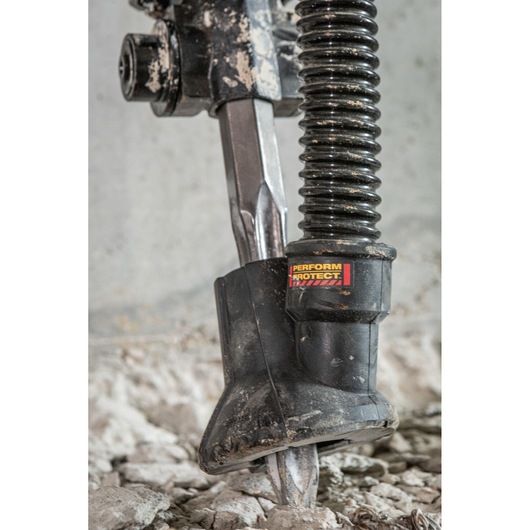 Close-up of DEWALT tool in use on concrete, showing chisel and dust extraction attachment.