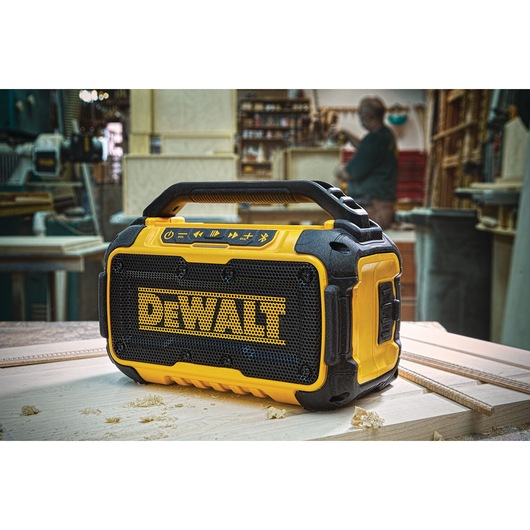 DEWALT portable Bluetooth speaker on a workbench in a workshop setting.