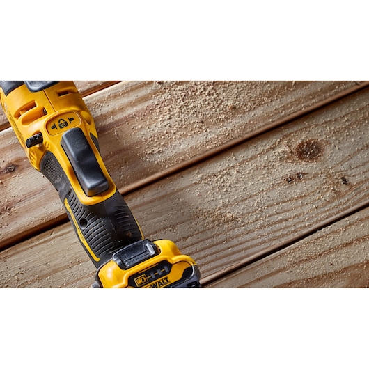 DEWALT cordless tool rests on wooden planks with sawdust scattered on the surface.