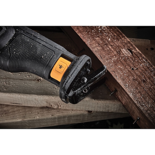 Close-up of a DEWALT reciprocating saw cutting through wooden boards with nails and sawdust.