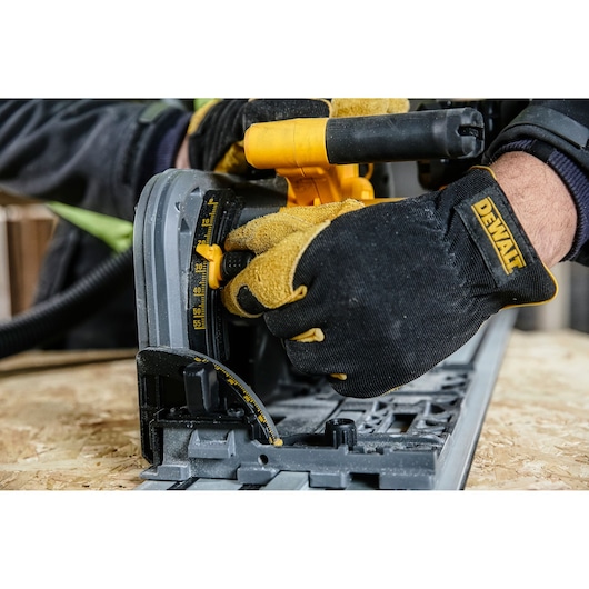 Close-up of a person wearing DEWALT branded work gloves adjusting the settings on a DEWALT power tool, positioned on a