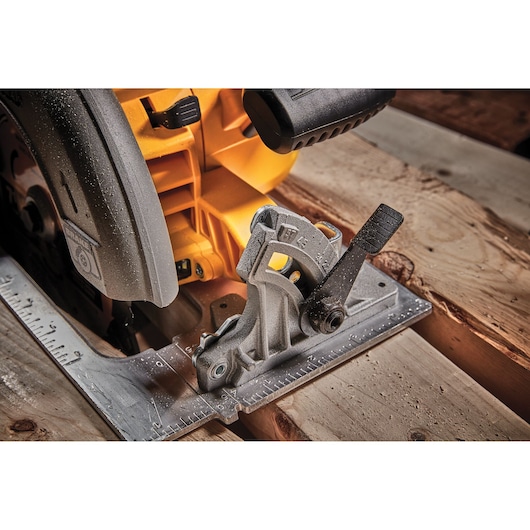 Close-up of a DEWALT circular saw cutting wood, showing the base and adjustment lever detail.