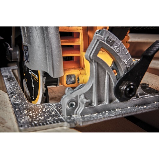 Close-up of a DEWALT circular saw in use on wood, showing blade and angle guide.