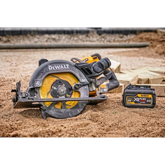 A DEWALT cordless circular saw with a yellow blade and a DEWALT XR FLEXVOLT 18V/54V lithium-ion battery pack placed on the