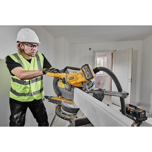 DEWALT DCS781X2-QW, DCS781X2 saw in use at a construction site. Worker cuts wood while wearing safety gear.