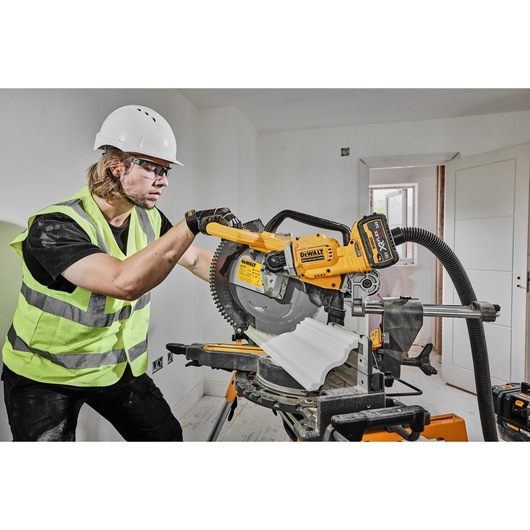 DEWALT DCS781X2-QW and DCS781X2 saw in use at a job site by worker in safety gear.