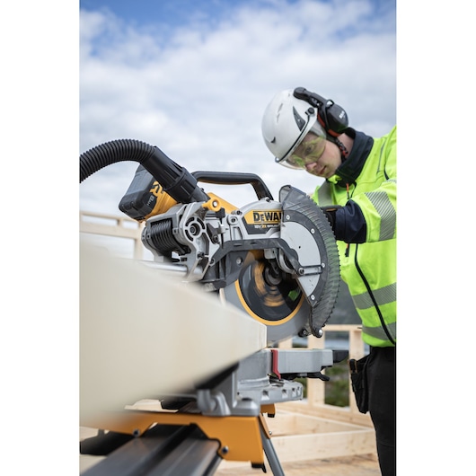 DEWALT DCS782N saw cutting wood outdoors, operated by a person in safety gear.
