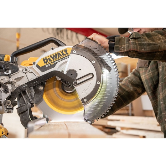 DEWALT cordless saw cutting wood with person operating, focus on blade and brand label.