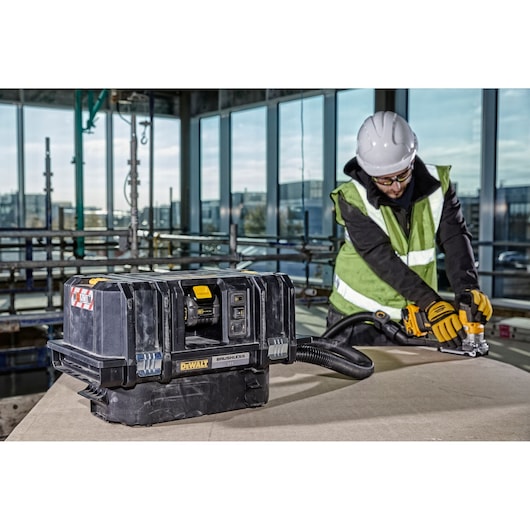 A DEWALT DCV586MT2 cordless brushless dust extractor placed on a table in a construction environment. In the background, a