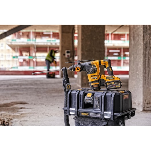 A DEWALT cordless rotary hammer drill with battery is shown on top of a DEWALT brushless dust extractor box in a