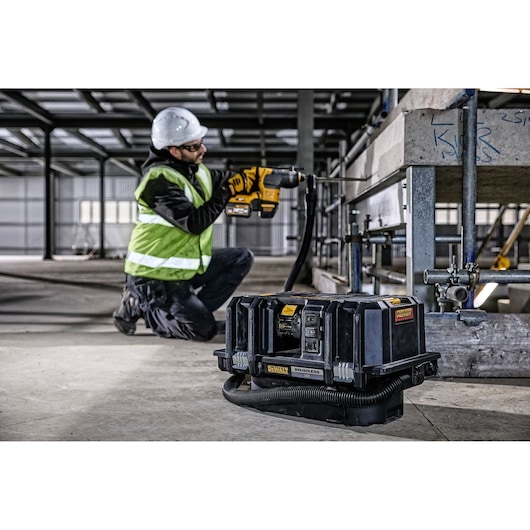 A DEWALT DCV586MT2 brushless portable dust extractor is placed on the floor of an industrial construction site. In the