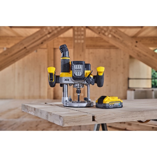 DEWALT cordless router with battery on a wooden workbench in a timber workshop setting.