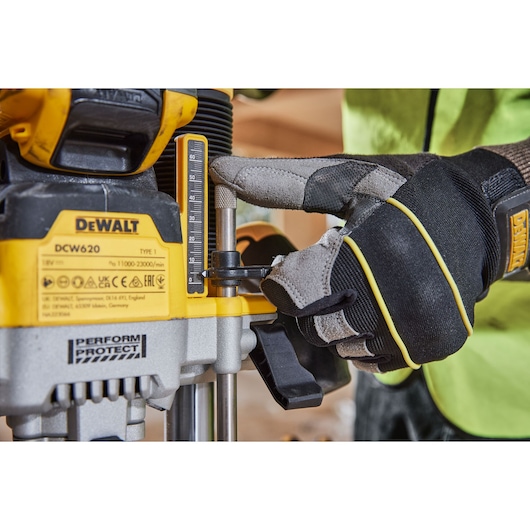 Close-up of gloved hand adjusting DEWALT DCW620H2 power tool depth gauge.