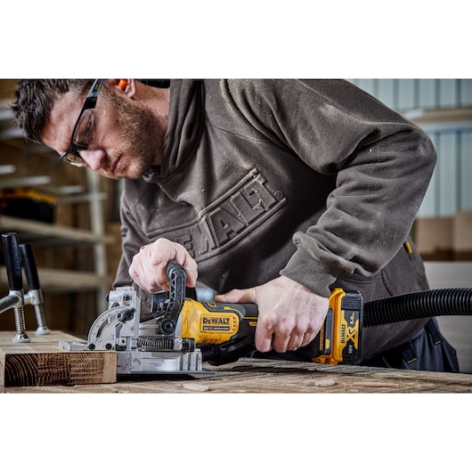 DEWALT DCW682P2-QW, DCW682P2 used for woodworking, person operating tool on wood surface. Photography.