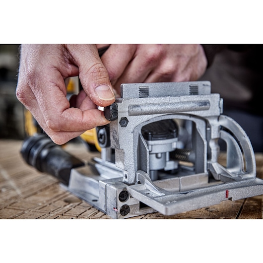 Hand adjusts DEWALT tool DCW682P2-QW, DCW682P2 on wood. Photography product close-up.