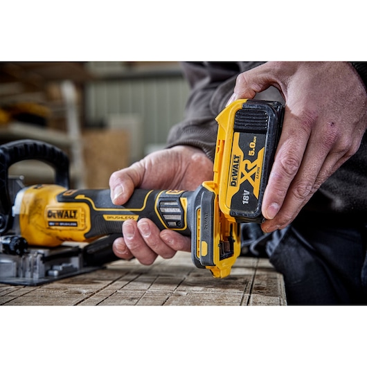 DEWALT DCW682P2-QW, DCW682P2 power tool in use, close-up on battery installation, woodworking workspace.