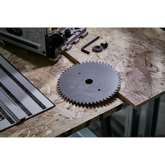 DEWALT saw blade and parts placed on a wooden workbench next to a power tool and guide rail.
