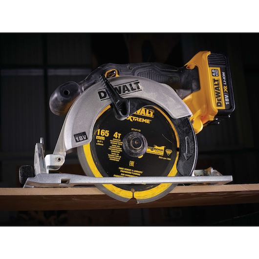 DEWALT DT1471 18V cordless circular saw, close-up on blade, cutting wood in workshop setting.