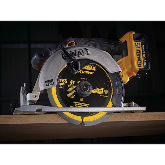 DEWALT 18V circular saw with a 165mm blade cutting wood, shown close-up in a workshop setting.