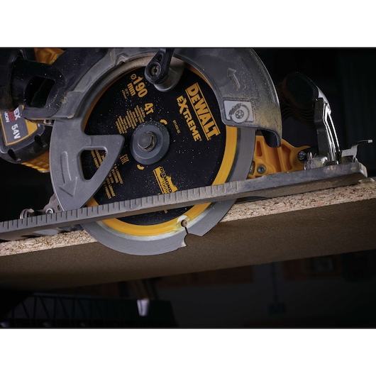 Close-up of a DEWALT Extreme circular saw cutting through a wooden board.