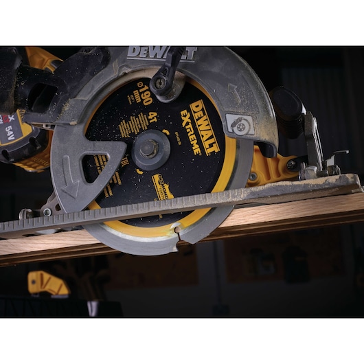 Close-up of a DEWALT circular saw cutting wood, showing the blade and part of the tool during operation.