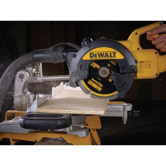 A DEWALT circular saw cutting through a piece of wood, with sawdust being expelled and the tool's brand name visible on the
