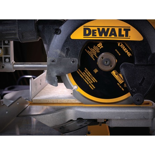 Close-up of a DEWALT circular saw cutting tile, showing blade detail and part of the saw base.