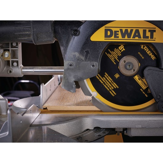 Close-up of a DEWALT circular saw cutting a wooden board on a workbench.
