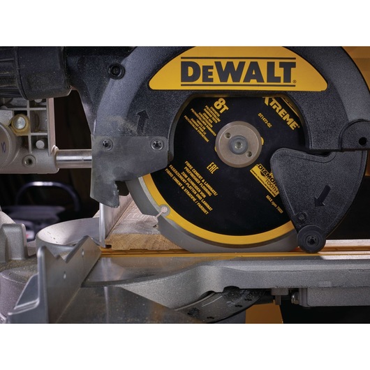 Close-up of a DEWALT DT1473 circular saw blade cutting wood on a mitre saw.