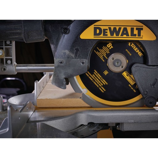 Close-up of a DEWALT circular saw cutting wood, showing blade and guard in action.